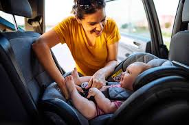 A woman smiles while holding a baby in a car seat, showcasing a safe and comfortable travel experience.